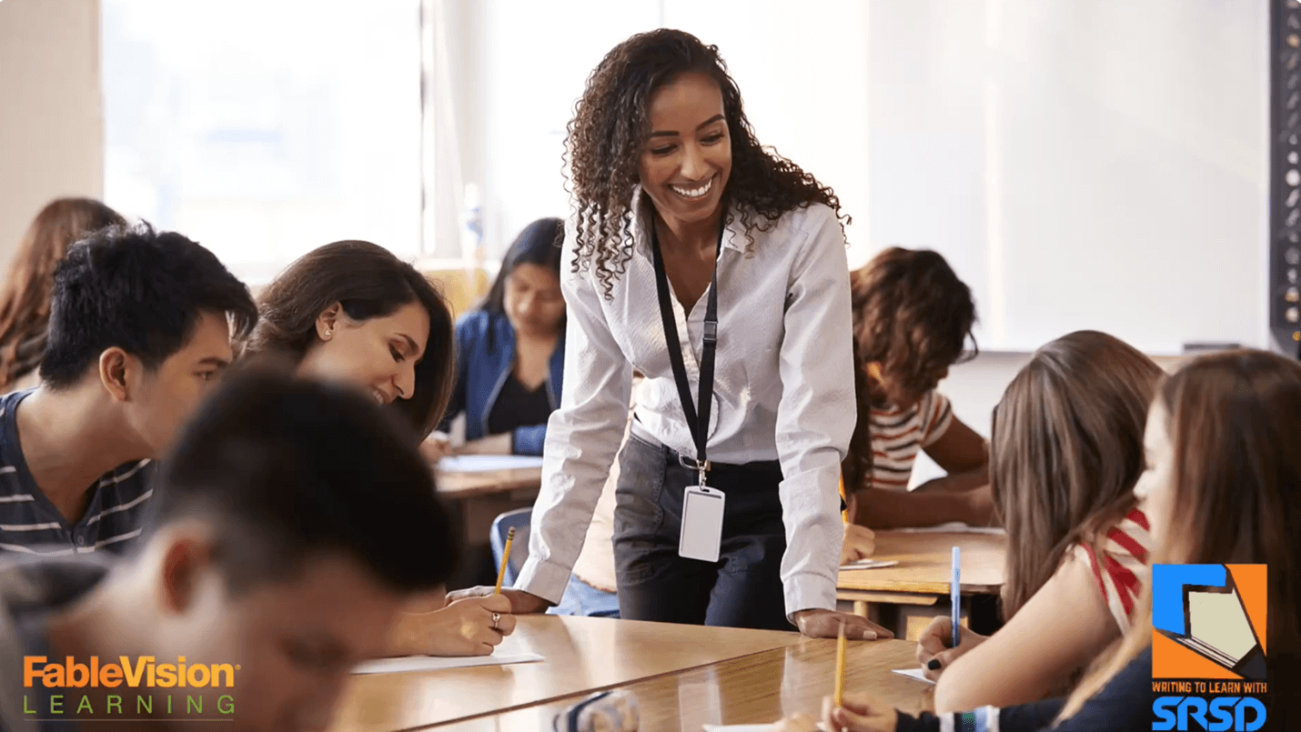 Teacher smiling and engaging with students in a classroom setting, with students focused on their writing tasks. Logos for FableVision Learning and Writing to Learn with SRSD are displayed in the bottom corners.