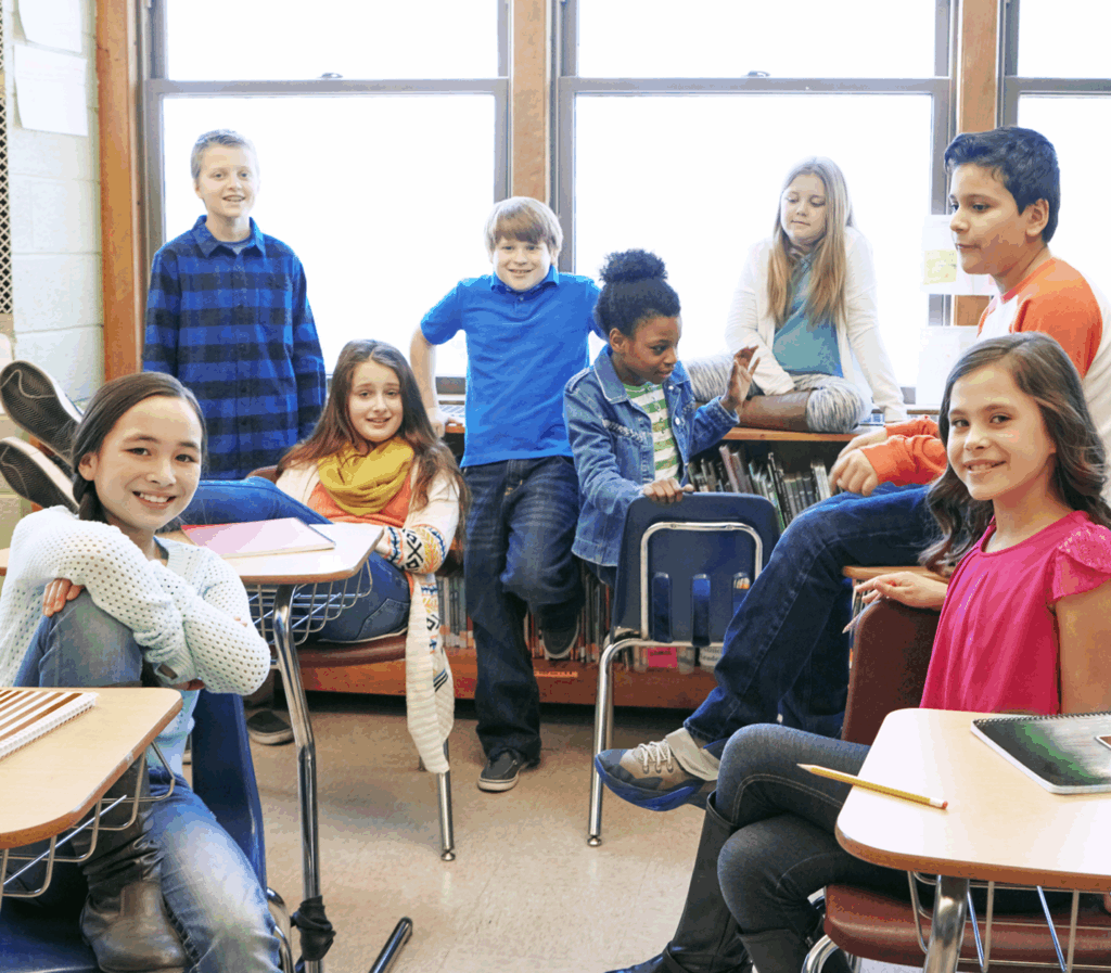 Diverse group of elementary students smiling in a bright classroom setting.