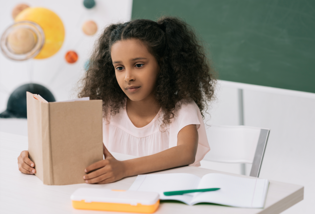Young girl reading a book in a classroom