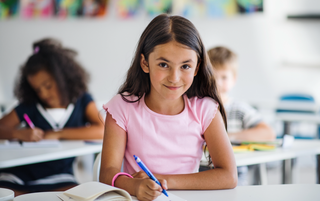 Elementary student writing in notebook during SRSD-based writing instruction in a classroom.