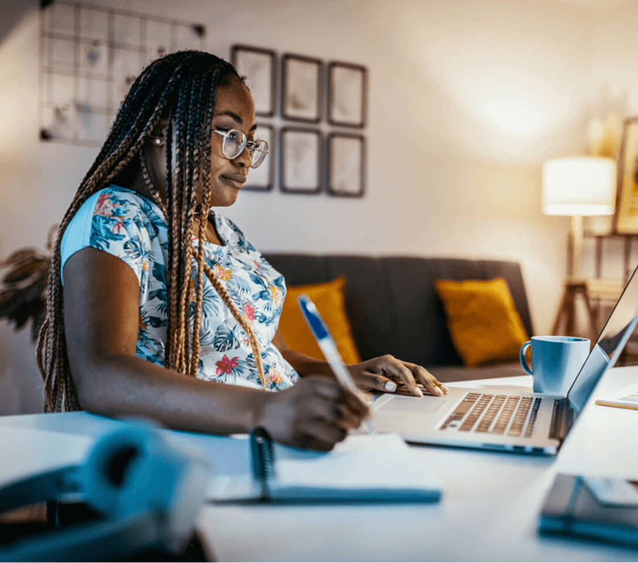 Educator writing in a notebook at a laptop